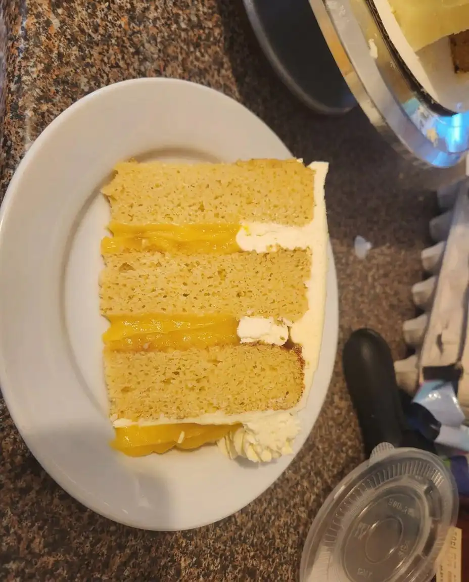 Applying thick vanilla frosting to the layers of an orange cake.
