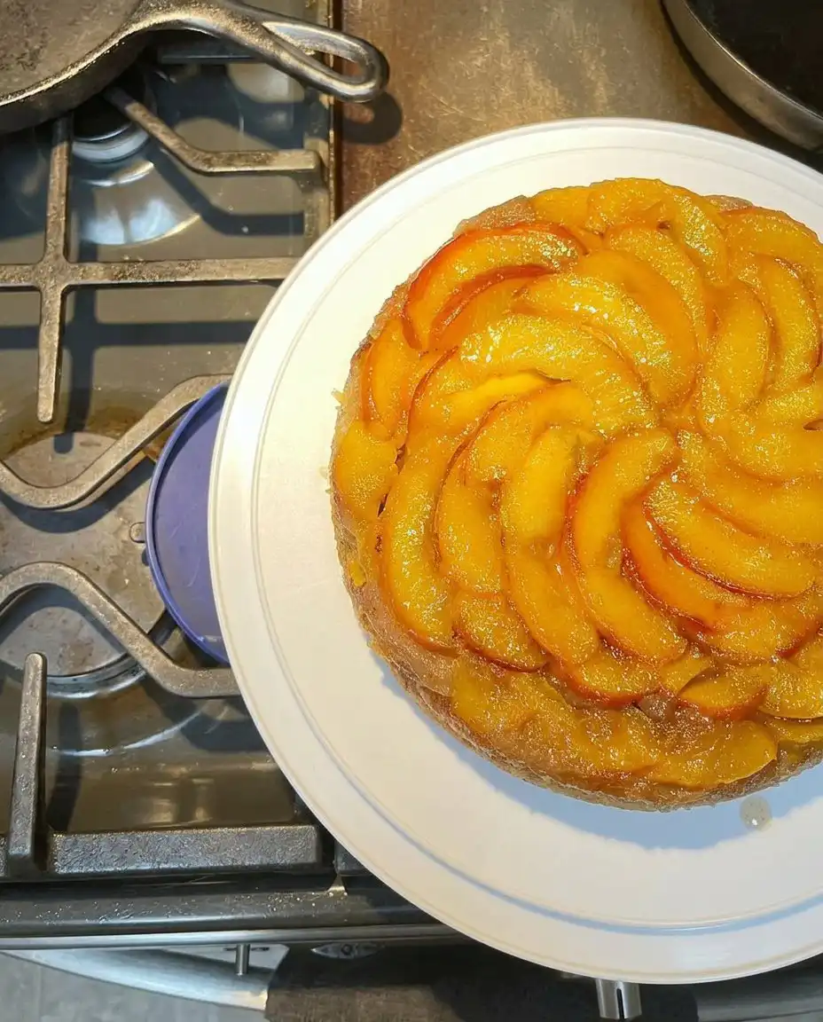 Bourbon Peach Upside Down Cake 10 A golden bourbon peach upside down cake on a white cake stand with a glistening caramel glaze.