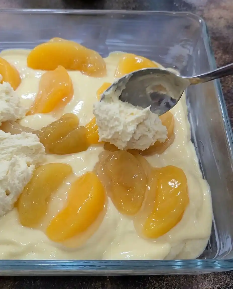 A 9x13 baking dish containing freshly baked golden Peaches and Cream Bars.