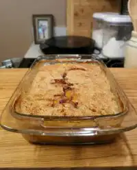 A golden brown super easy peach cobbler fresh from the oven in a glass baking dish