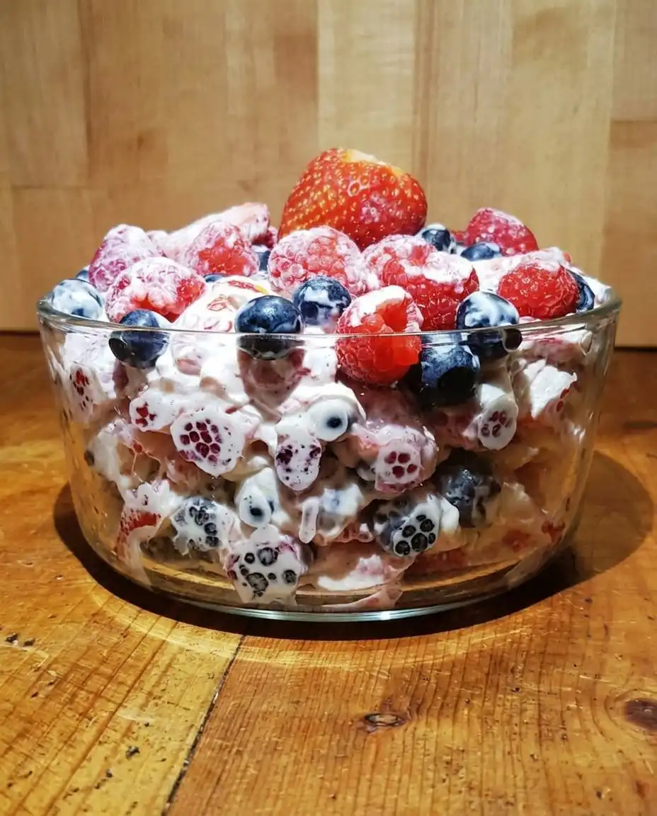 Small clear cups filled with cheesecake salad topped with a blueberry and mint leaf