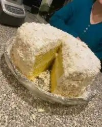 A slice of Italian Lemon Cream Cake showing four thin layers and lemon zest garnish