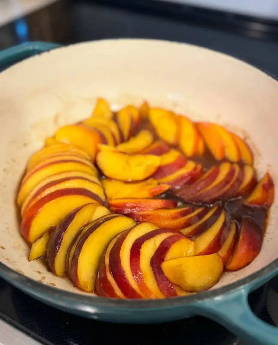 Bourbon Peach Upside Down Cake 13 Amber bourbon caramel being poured over peach wedges in a cake pan.
