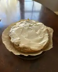 A moist zucchini banana cake with thick maple cream cheese frosting on a rustic table