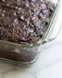 A thick slice of Old-Fashioned Chocolate Zucchini Cake resting on a rustic wooden board in a farmhouse kitchen.
