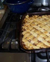 A golden brown Old-Fashioned Oven-Baked Peach Cobbler in a white ceramic dish.