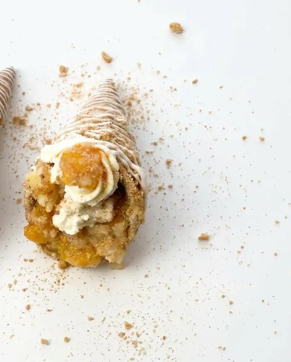 Peach Cobbler Cheesecake Cones 10 A group of golden Peach Cobbler Cheesecake Cones arranged on a rustic wooden platter.