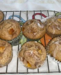 Freshly baked Homemade Peach Cobbler Muffins 2 with golden streusel topping on a plate