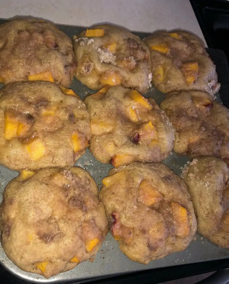 A batch of 12 peach cobbler muffins cooling on a wire rack.