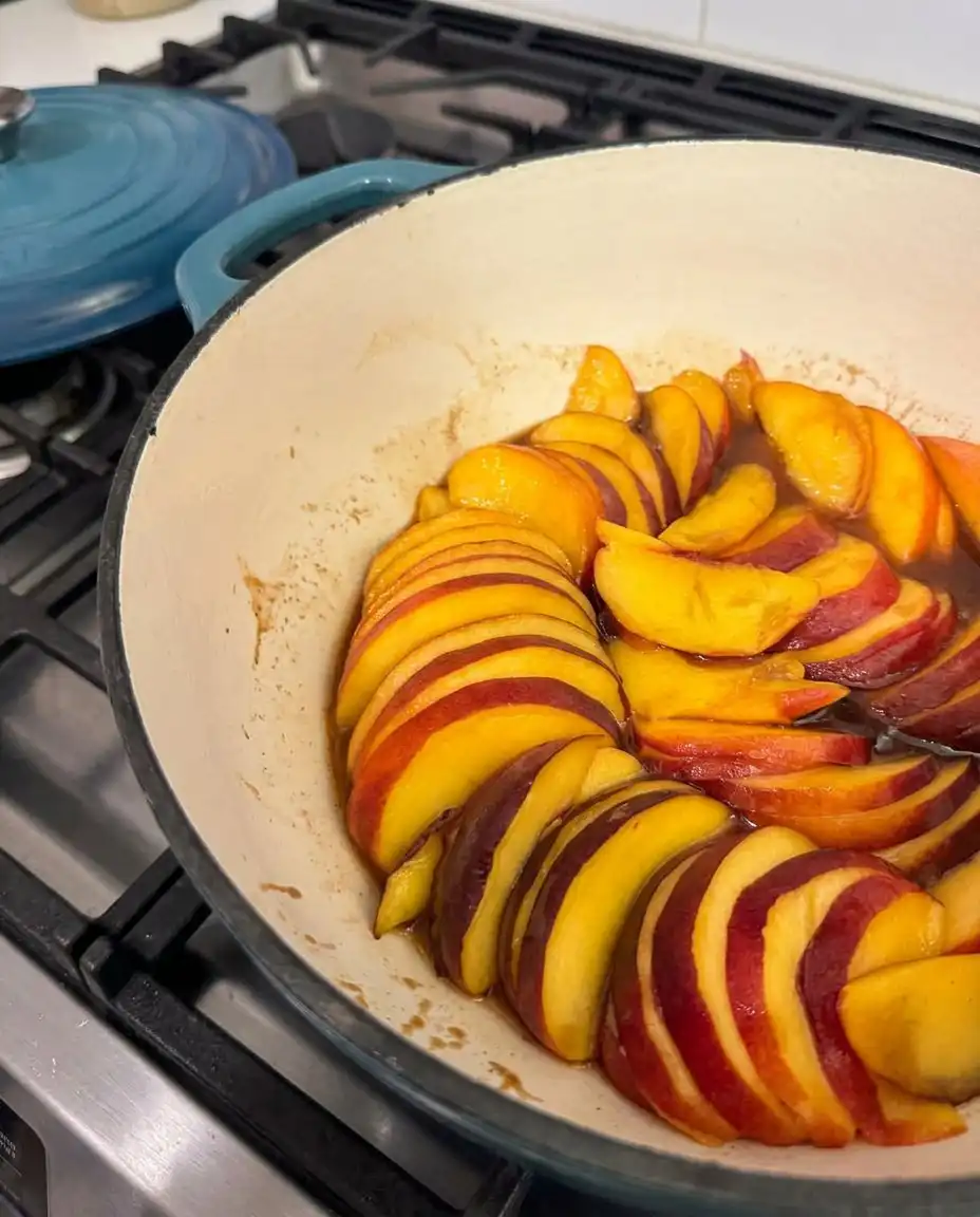 Fresh peach slices arranged over a brown sugar and butter mixture in a baking pan