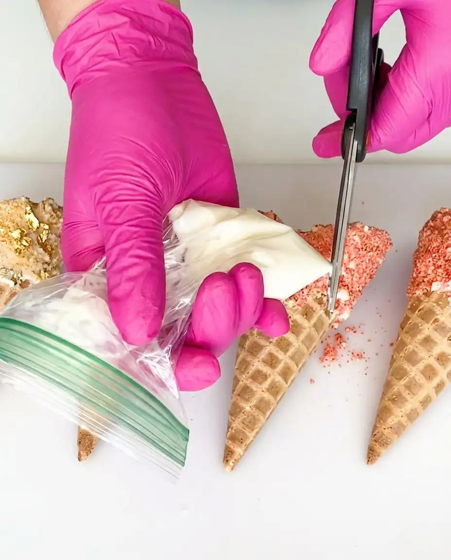 Peach Cobbler Cheesecake Cones 13 A person piping creamy cheesecake filling into a white chocolate lined waffle cone.