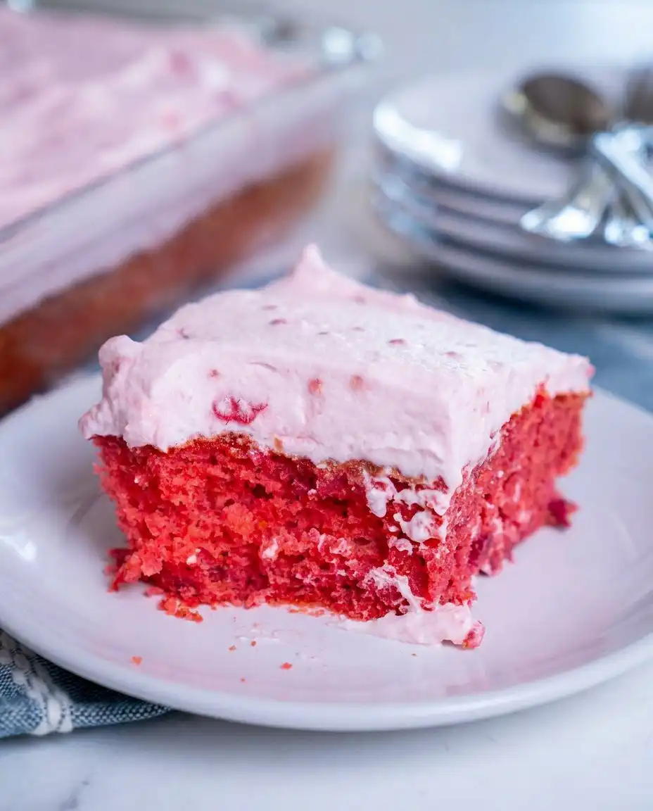 A single square slice of raspberry fluff cake on a white plate with mint
