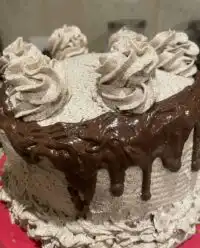A soft Oreo cookies and cream cake sitting on a rustic wooden farmhouse table.