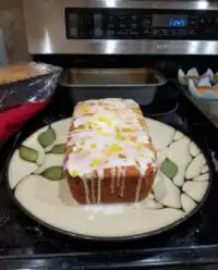 Two mini loaves of lemon zucchini bread with a white glaze on a wooden board