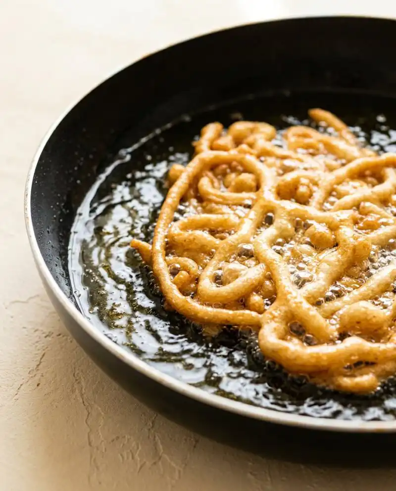 A golden brown Pumpkin Spice Funnel Cake dusted with powdered sugar on a plain plate.
