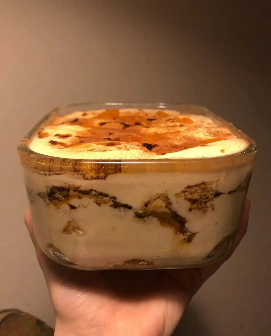 A square slice of peach tiramisu on a white plate with a fork