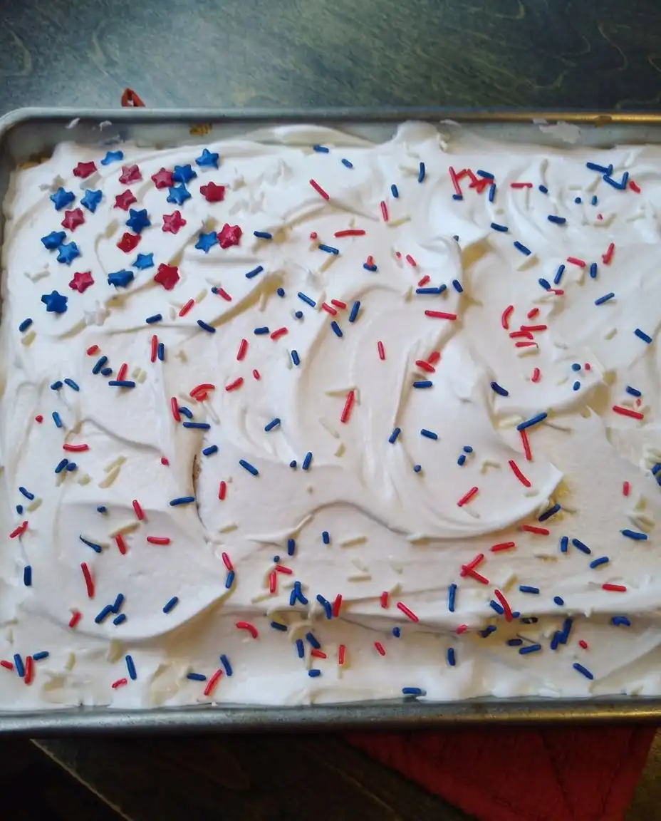 Red, White & Blue Patriotic Poke Cake 14 A slice of Red, White & Blue Patriotic Poke Cake served on a white plate.