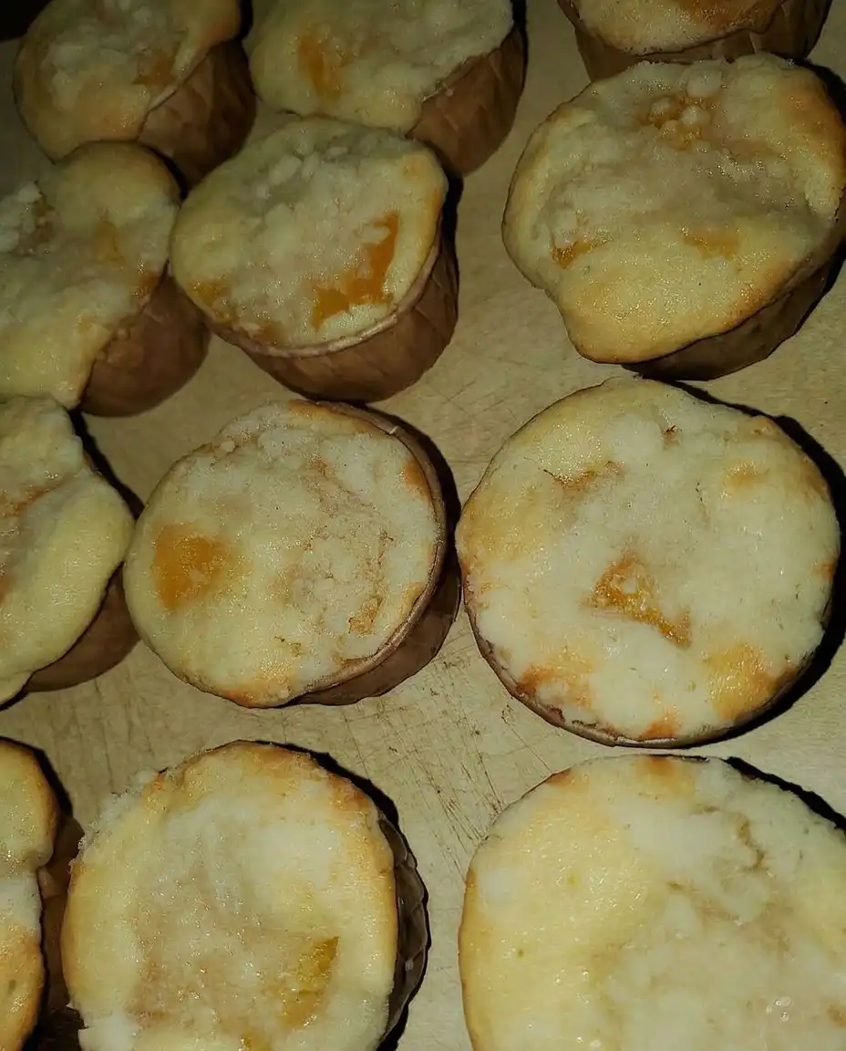 Three peach cobbler muffins arranged on a white wire cooling rack with a linen napkin.