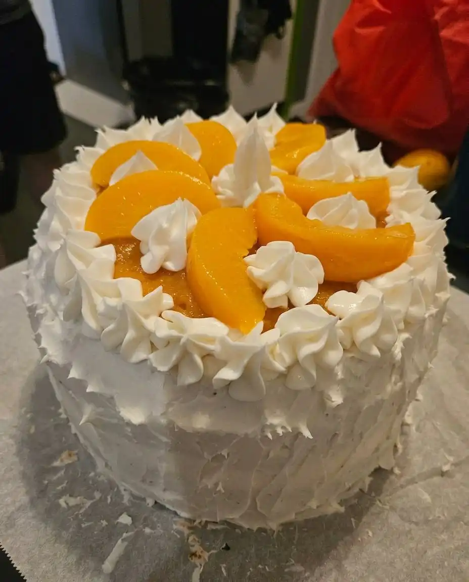 A slice of peach layer cake served on a rustic wooden table outdoors.