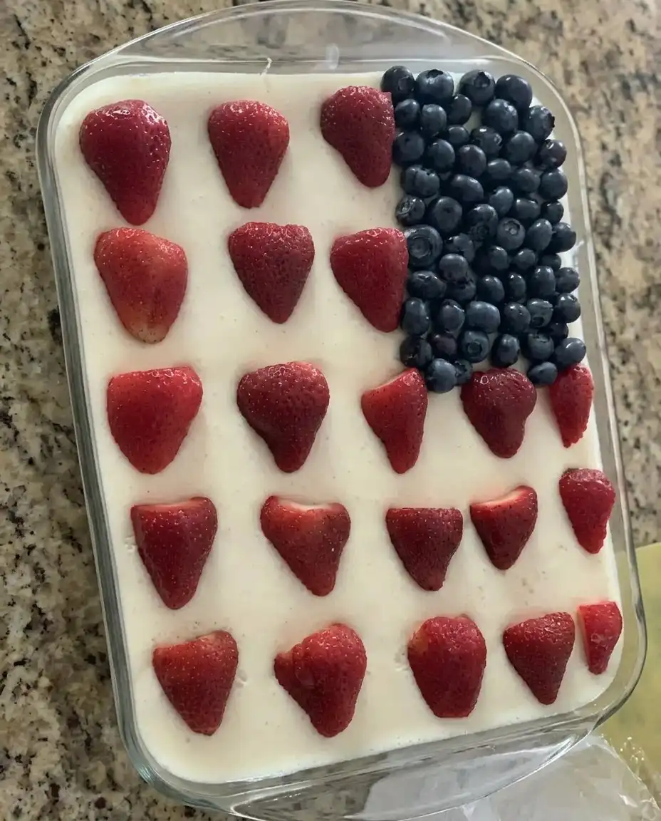 A slice of American flag cake served on a white plate at an outdoor picnic