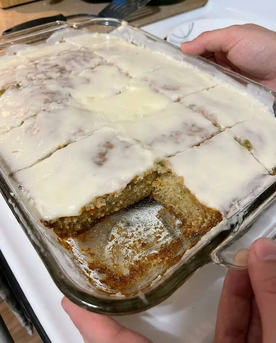 Two zucchini bars with caramel frosting served on a white porcelain plate with a fork