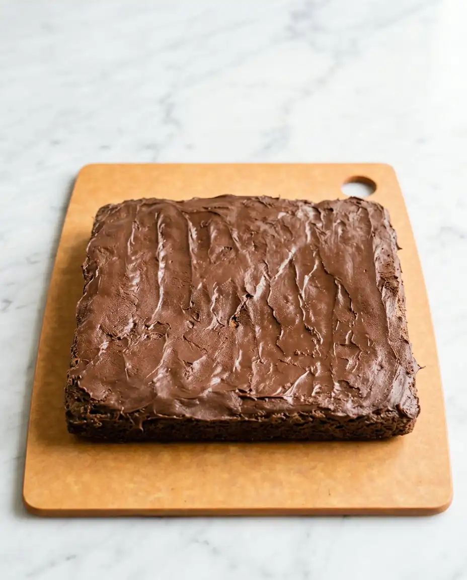 A thick slice of chocolate zucchini cake with walnuts served on a white ceramic plate.