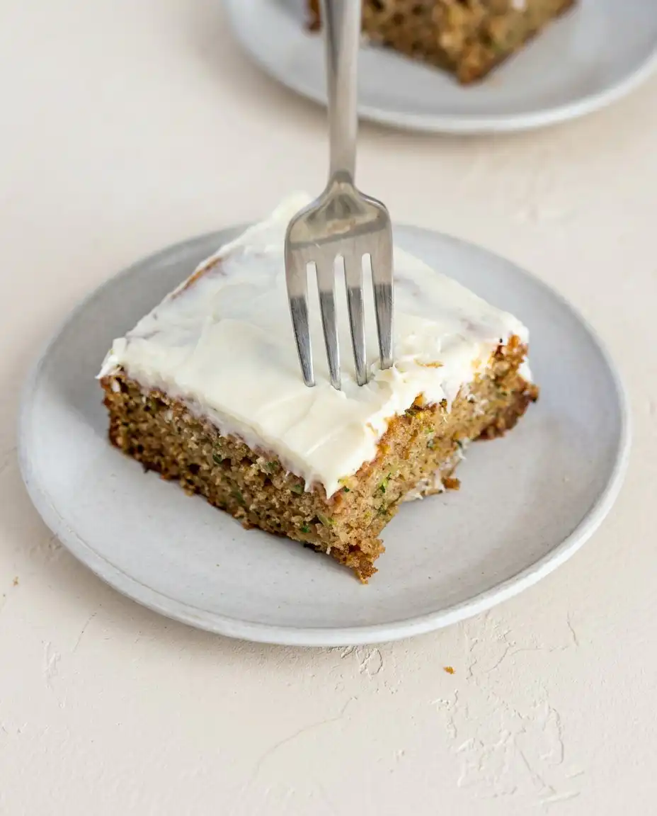 Several slices of Classic Zucchini Cake with Cream Cheese Frosting on a serving platter.