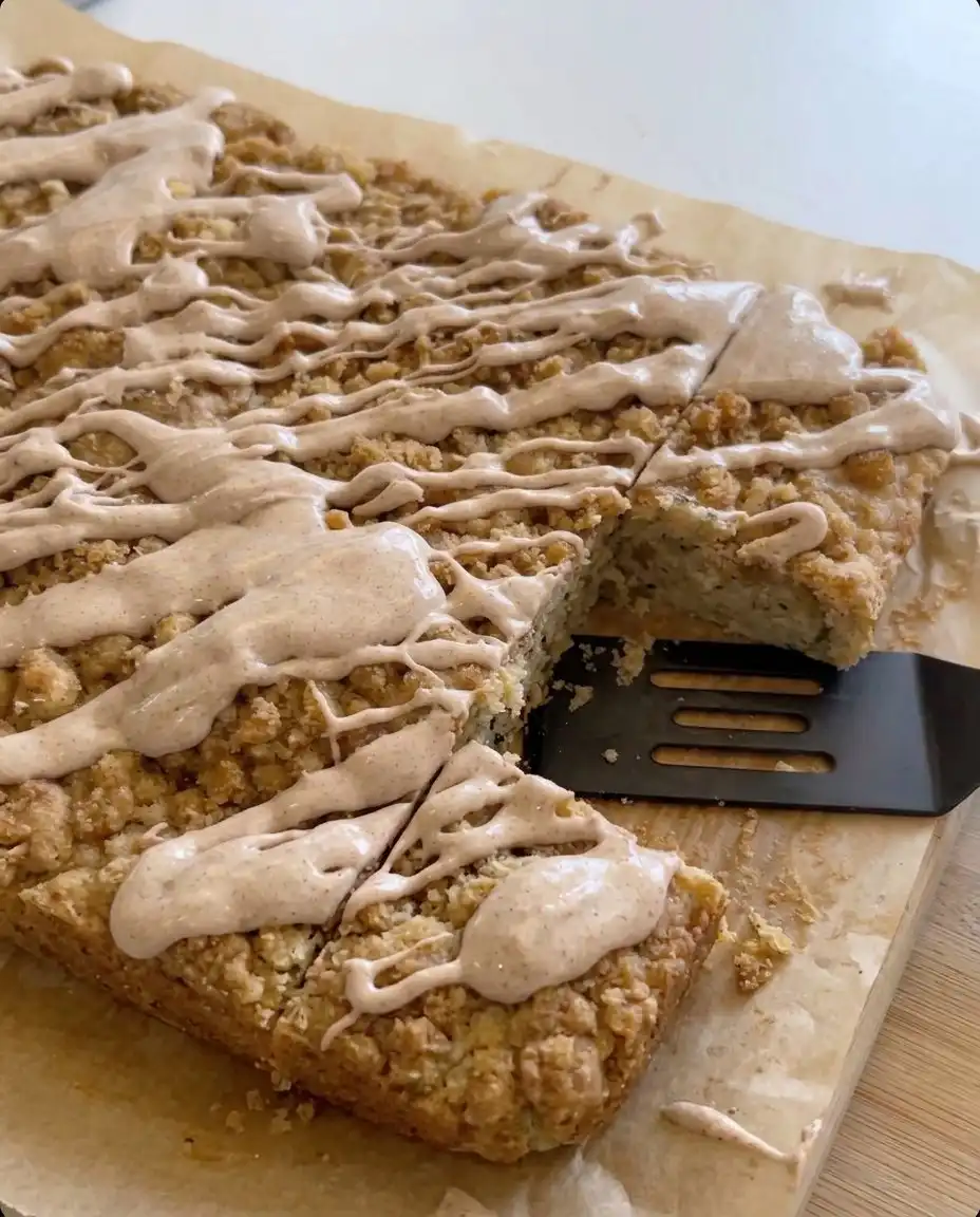 A square of zucchini crumb cake with cinnamon glaze on a white plate