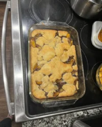 A close up view of golden brown peach cobbler in a slow cooker with bubbling fruit