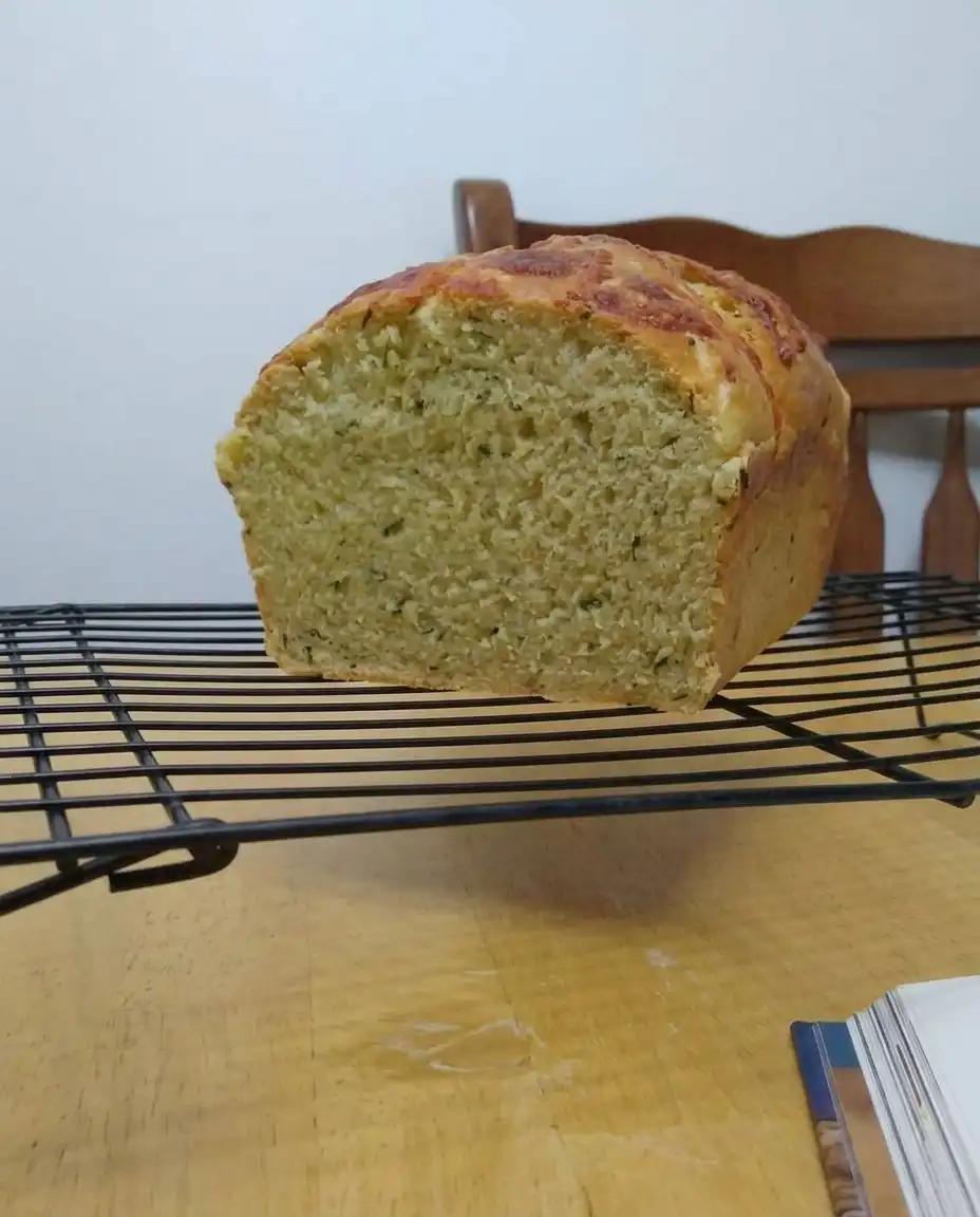 Green Onion Zucchini Cheddar Quick Bread 13 A hand squeezing shredded zucchini in a paper towel to remove excess liquid