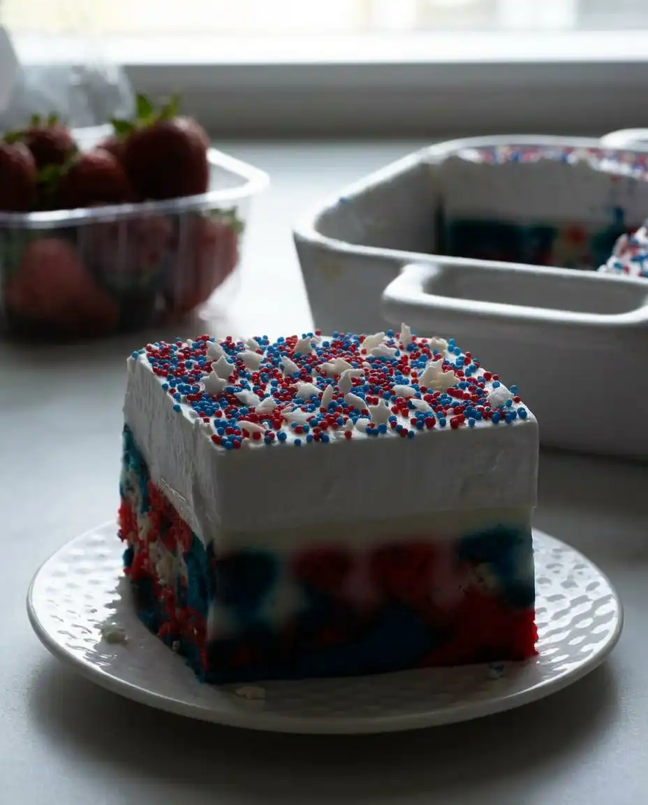 A toothpick swirling red, white, and blue cake batter in a baking pan