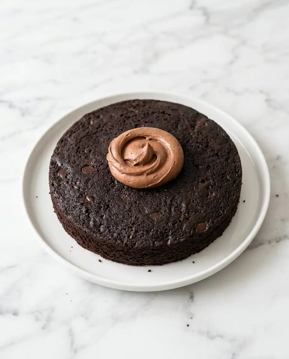 A hand inserting an instant read thermometer into a Classic Chocolate Zucchini Cake layer.