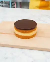 A close up shot of a Two-Layer Boston Cream Cake showing the thick custard filling and chocolate glaze.