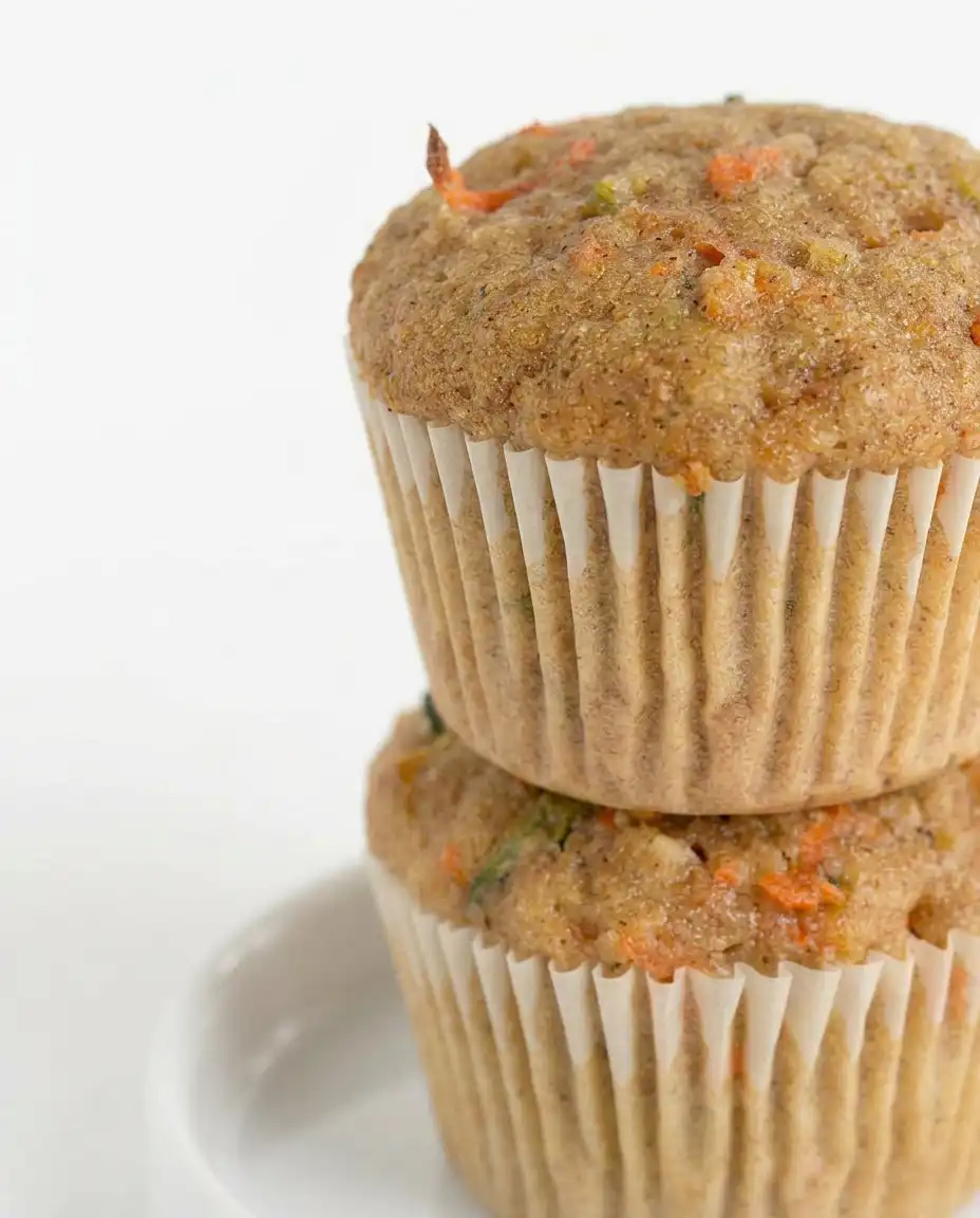 A basket of golden brown Zucchini Carrot Oatmeal Muffins lined with a linen cloth.
