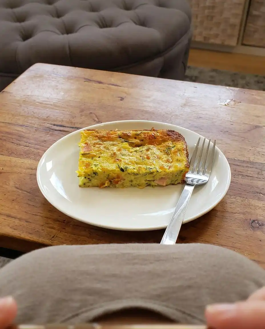A zucchini pie resting on a wire cooling rack to allow the proteins to set.