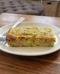 A close up cross section of a savory zucchini pie showing distinct layers of zucchini slices and a golden Parmesan crust.