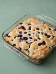 Freshly baked golden brown blueberry buttermilk breakfast cake cooling on a wire rack in a home kitchen