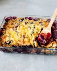 A fresh 3-Ingredient Blueberry Dump Cake baking in a glass dish with a golden crust.
