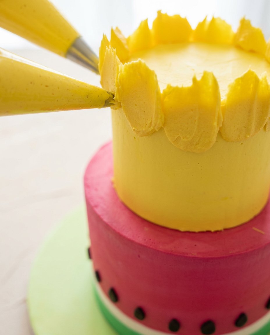 Watermelon and Pineapple Tropical Fruit Cake 15 Hands carving a large watermelon into circular layers for a Watermelon and Pineapple Tropical Fruit Cake