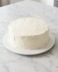 A beautiful slice of Classic Carrot Cake with Cream Cheese Frosting displayed on a glass cake stand.