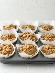 Freshly baked Classic Coffee Cake Muffins cooling on a windowsill in a rustic kitchen.