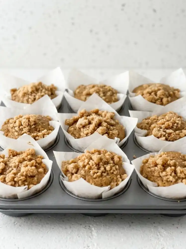 Freshly baked Classic Coffee Cake Muffins cooling on a windowsill in a rustic kitchen.