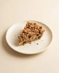 A freshly baked golden Old-Fashioned Peach Cake bubbling in a ceramic casserole dish on a cooling rack.