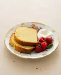 A beautifully sliced classic pound cake resting on a vintage glass cake stand.