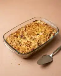 A warm golden Classic Pumpkin Dump Cake topped with toasted pecans in a baking dish.