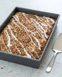 A fresh baked Classic Streusel Coffee Cake in a metal baking pan showing a thick cinnamon sugar crumble topping