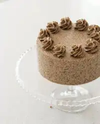 A gorgeous double layer Cookies and Cream Birthday Cake displayed on a vintage glass cake stand.