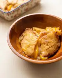 A beautifully sliced piece of peach cobbler sheet cake showing the delicate crumb and peach layers.