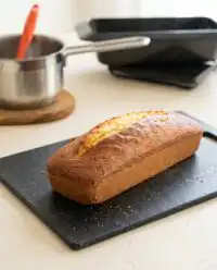 A golden brown loaf of classic Vanilla Pound Cake cooling on a metal wire rack.