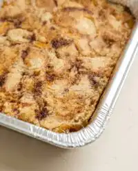 A rustic peach cobbler with white cake mix baking in a dish cooling on a farmhouse windowsill.